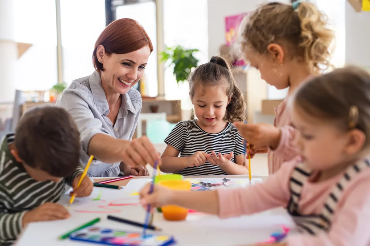 une jeune femme entourée d'enfants faisant du coloriage