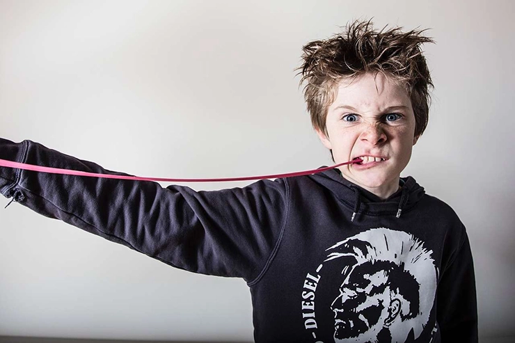un enfant faisant une grimace avec un chewing-gum en bouche