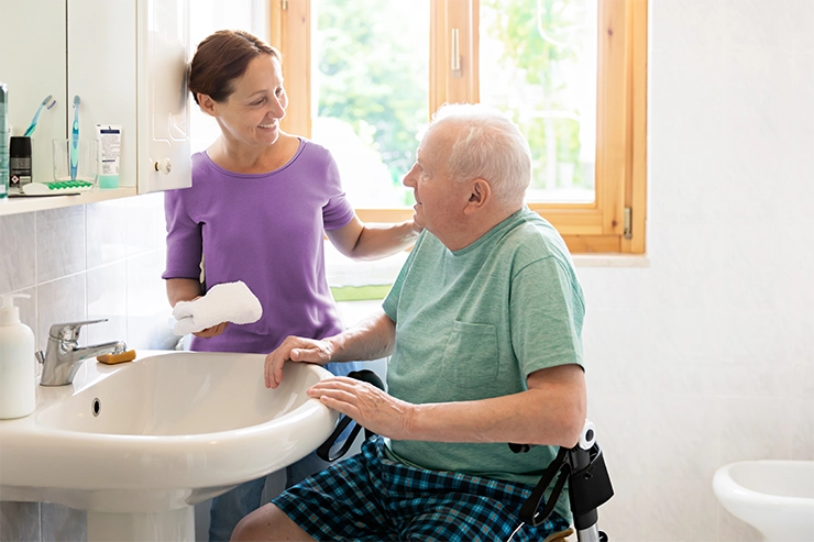 Une aide soignante aidant un vieil homme en situation de handicap